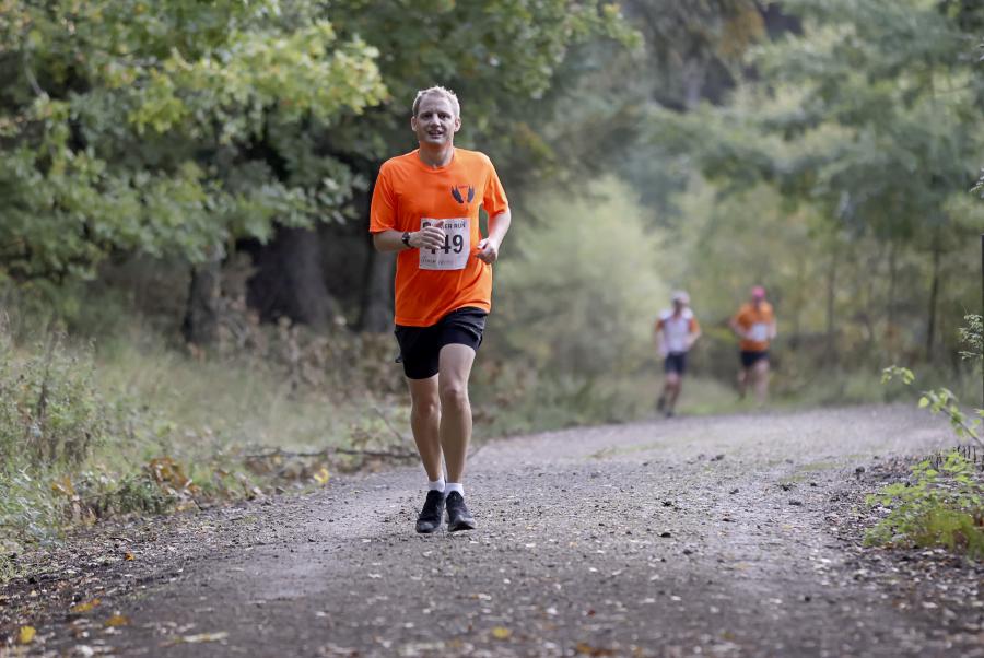 A photo of Geoffrey running through the woods during an autumn half-marathon.