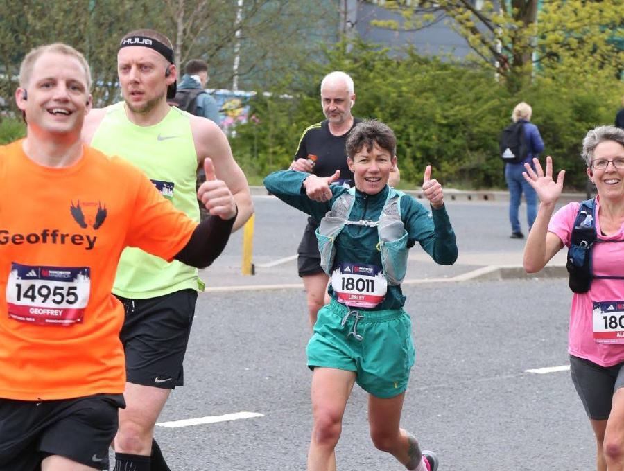 A photo of myself and others running with our thumbs up and smiling.